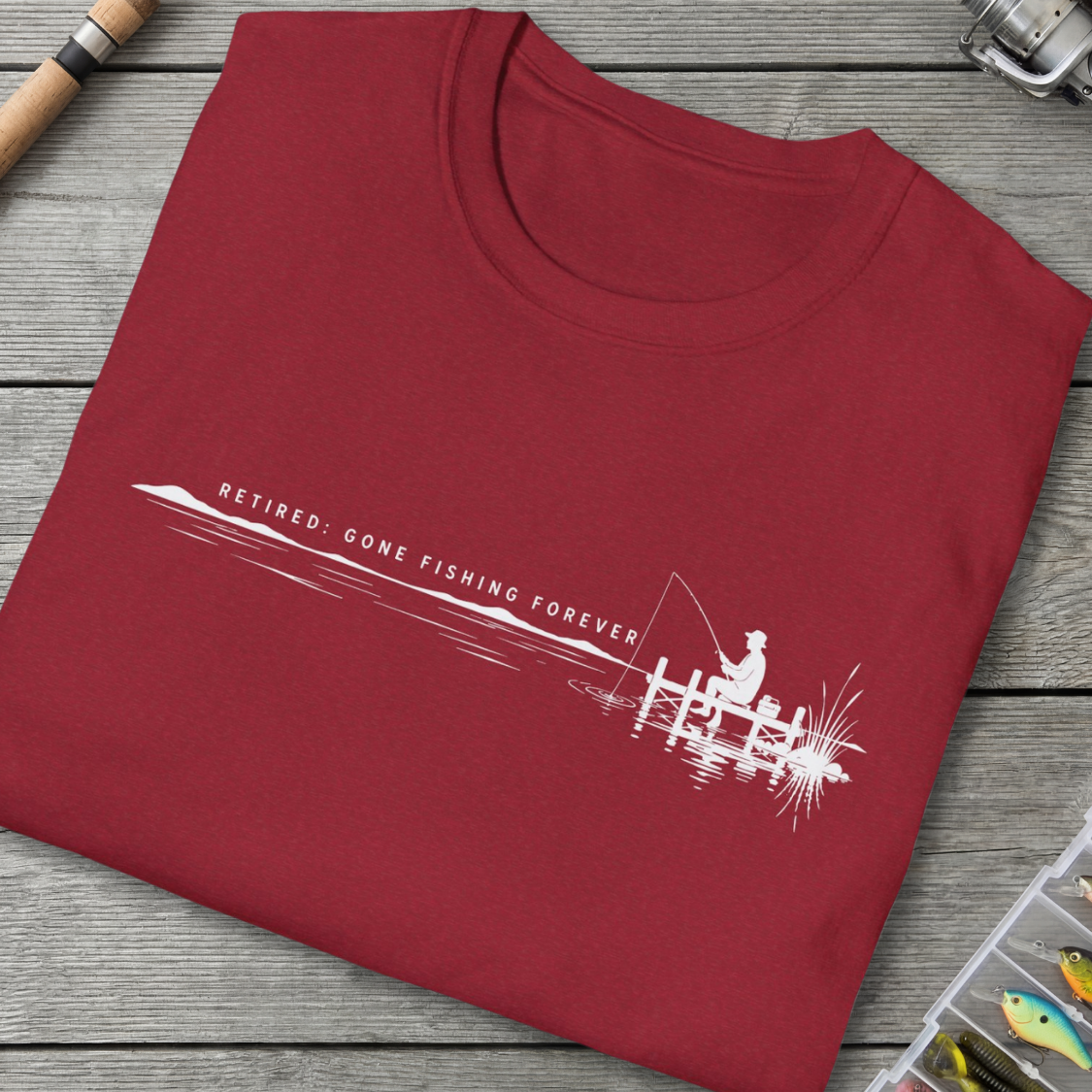Folded red t-shirt with fishing-themed design on a wooden surface