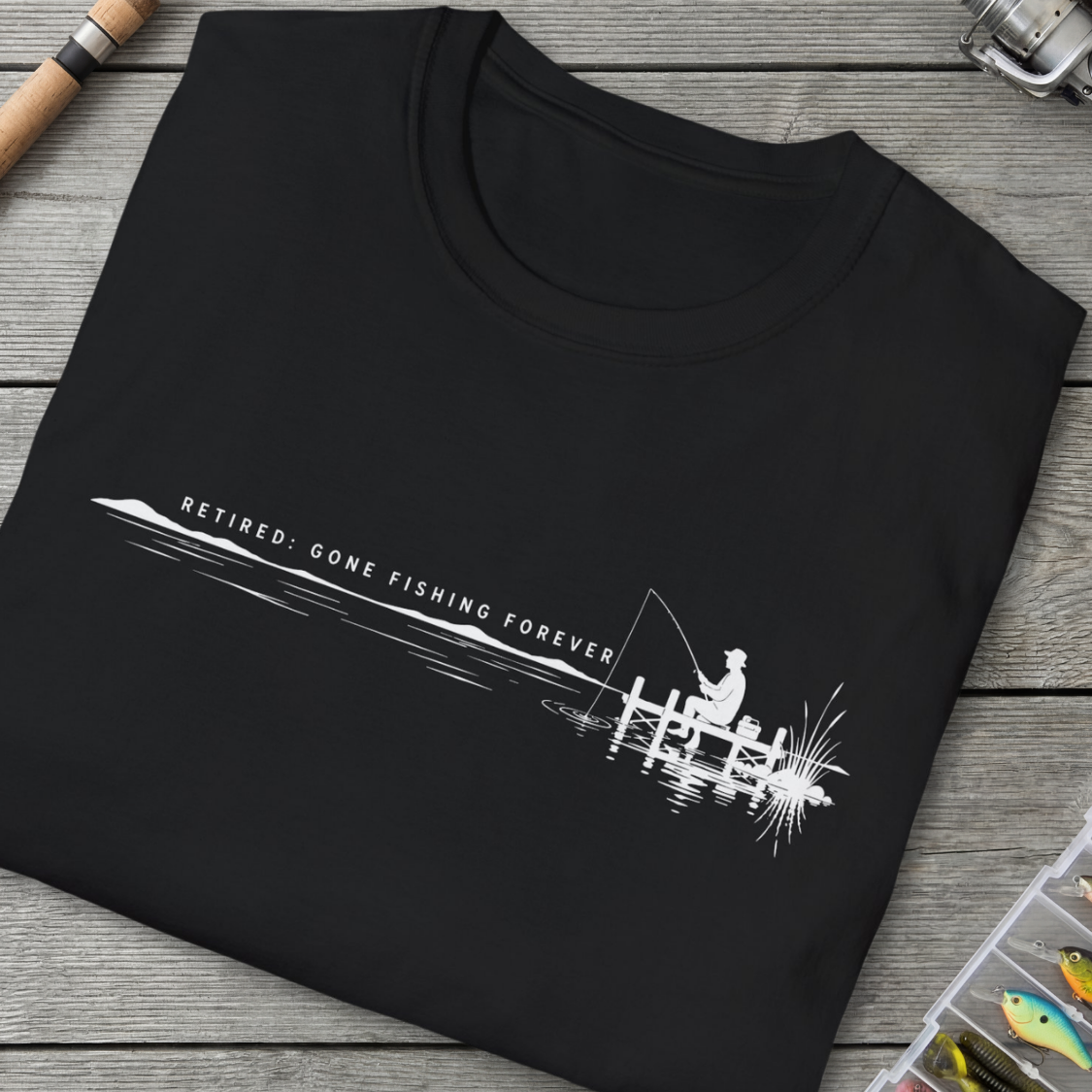 Black t-shirt with white fishing graphic and text on a wooden surface