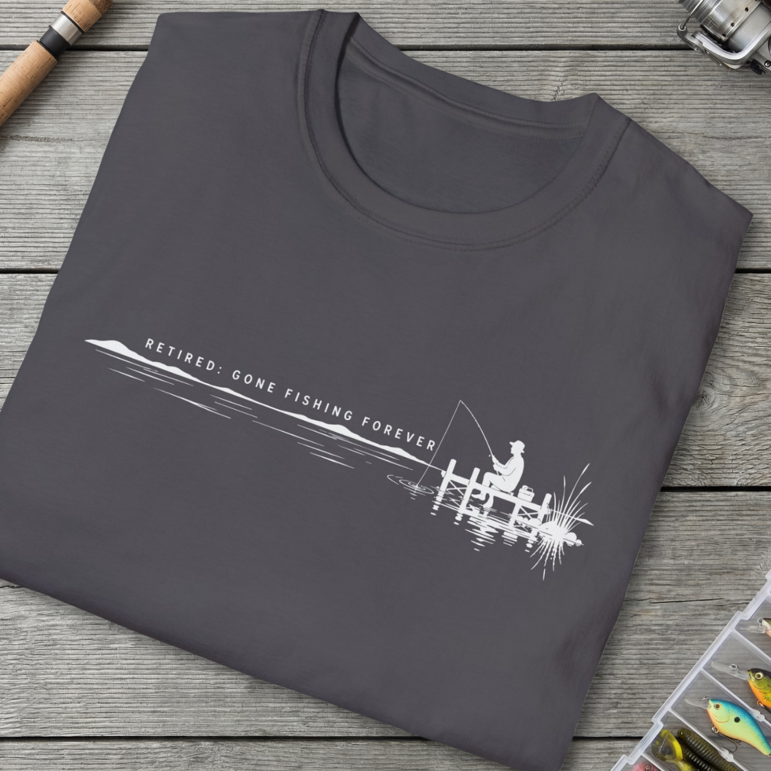 Folded gray t-shirt with fishing-themed design on a wooden surface