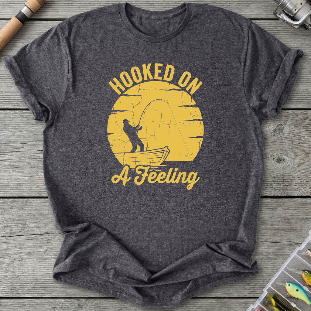 Gray t-shirt with yellow graphic and text 'Hooked on a Feeling' on a wooden surface.